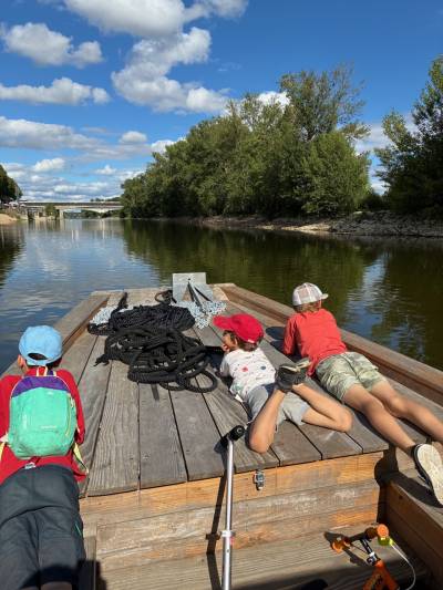 Trois enfants couchéa à plat ventre sur une barge qui sillonne sur la Loire à Orléans.