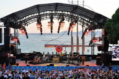 La scène de Jazz à Juan, ciel bleu, mer calme avec le scène au premier plan et le public.