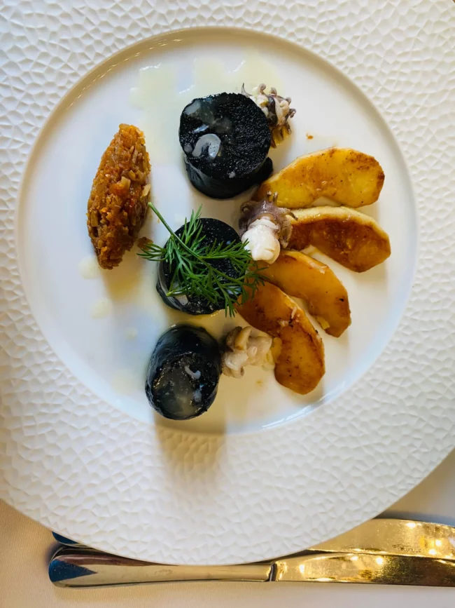 Une assiette gourmande avec des quenelles noires.