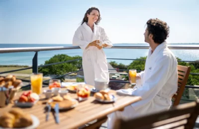 Un couple prend son petit dejeuner en peignoir devant la mer