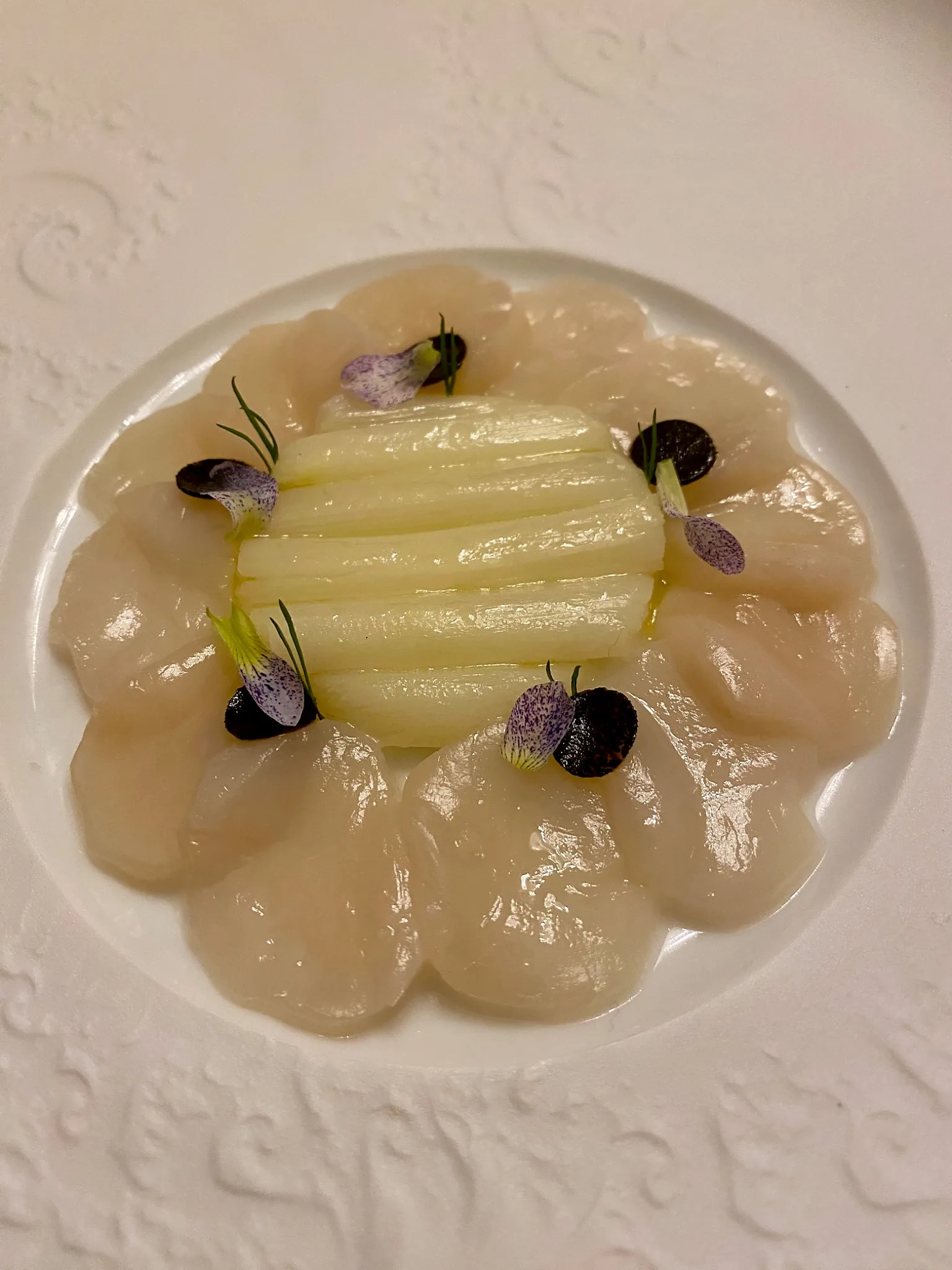 Assiette blanche présentant carpaccio de St Jacques et asperges blanches nouvelles.