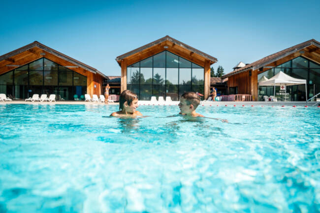 des enfants nagent dans une piscine découverte.