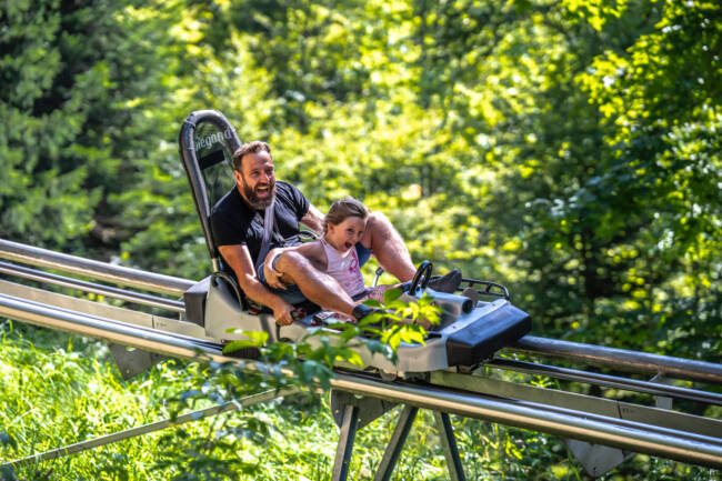 un père et sa fille font de la luge d'été