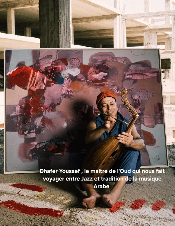 Un homme arba joue de l'Oud, asssis sur le sol devant une peinture colorée.